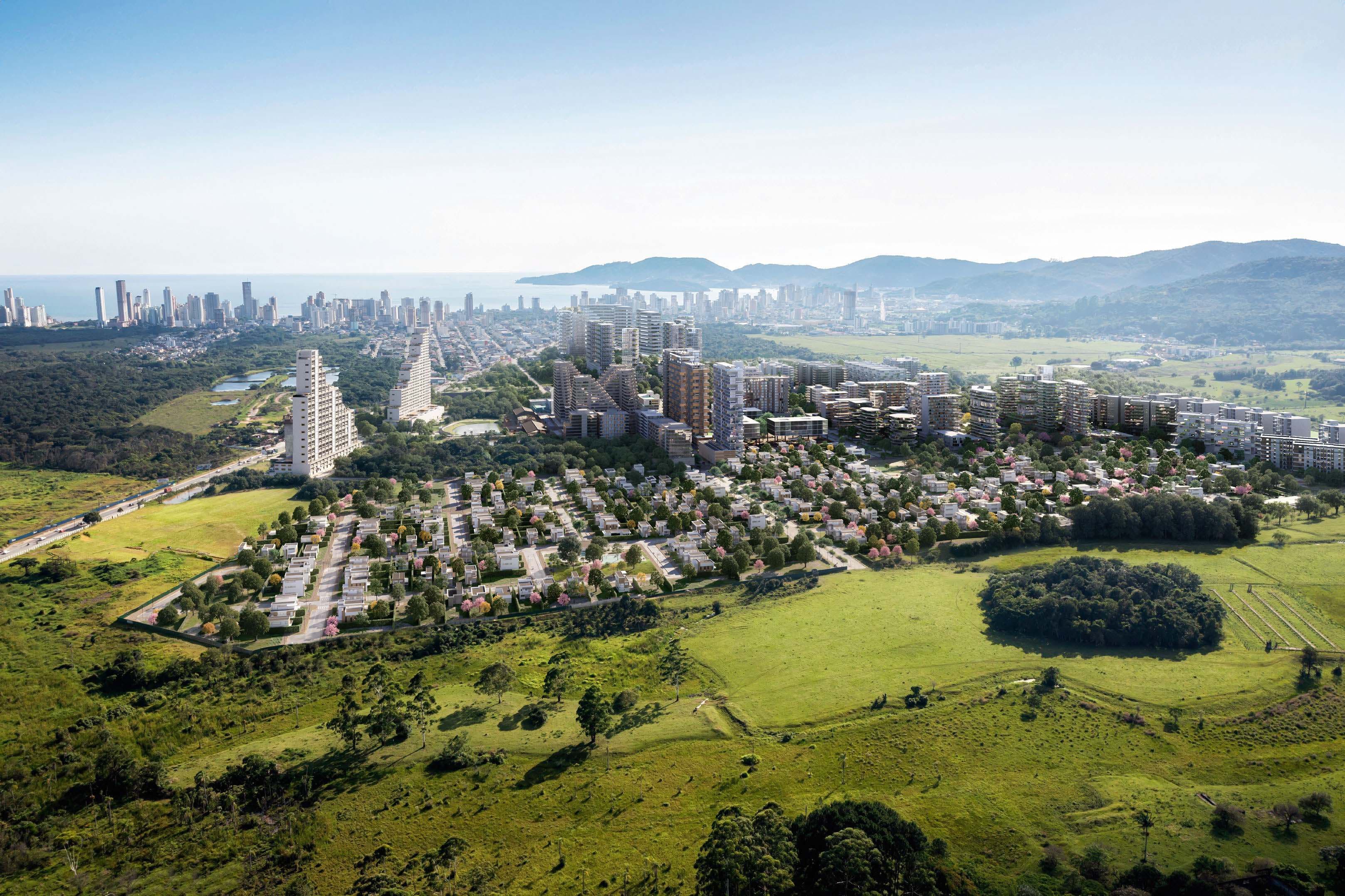 Renderização aérea de empreendimento urbano com torres residenciais, casas e áreas verdes, com cidade litorânea e mar ao fundo